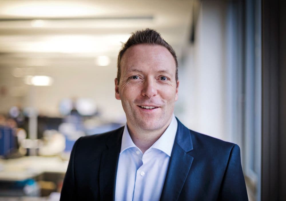 BOGE Aftermarket Ansprechpartner in formeller Kleidung steht in einem modernen Büro.