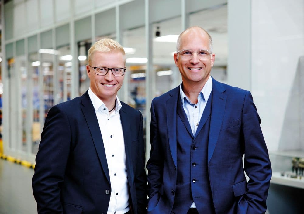 Björn Six und Sebastian Göbel nebeneinander als BOGE Geschäftsführung in einer hellen Fertigungshalle.