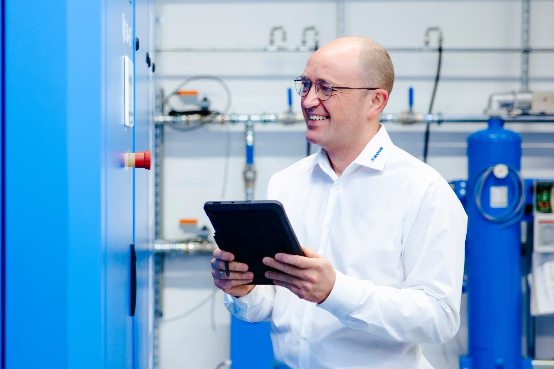 Ein BOGE Mitarbeiter steht vor einem Kompressor mit der richtigen Kompressorensteuerung auf seinem Tablet