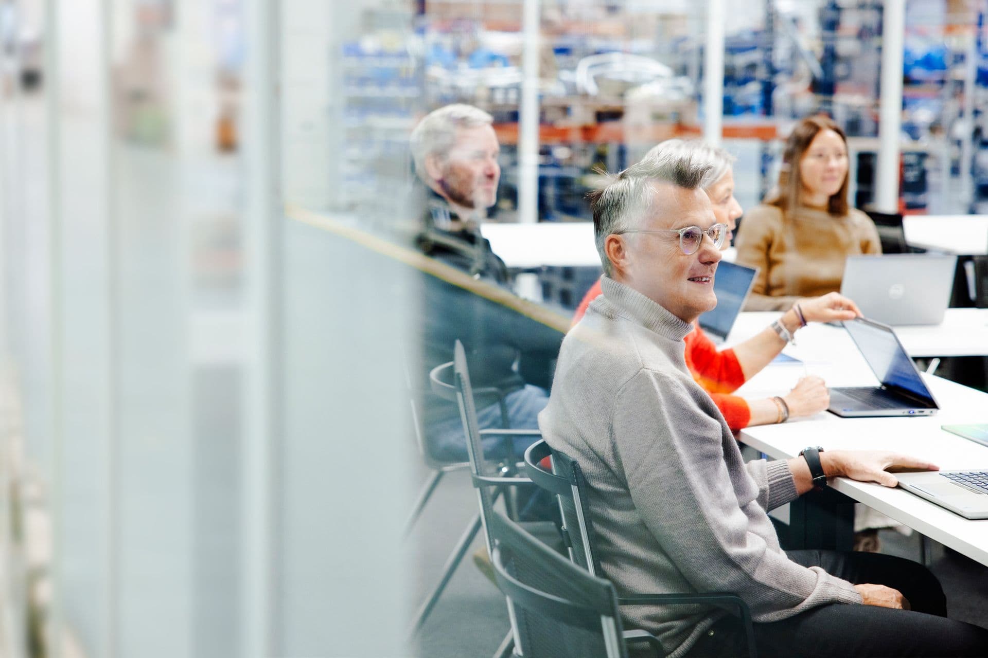 Schulungsteilnehmer in einem Schulungsraum in der Werkshalle von BOGE mit Computern vor sich an langen weißen Tischen