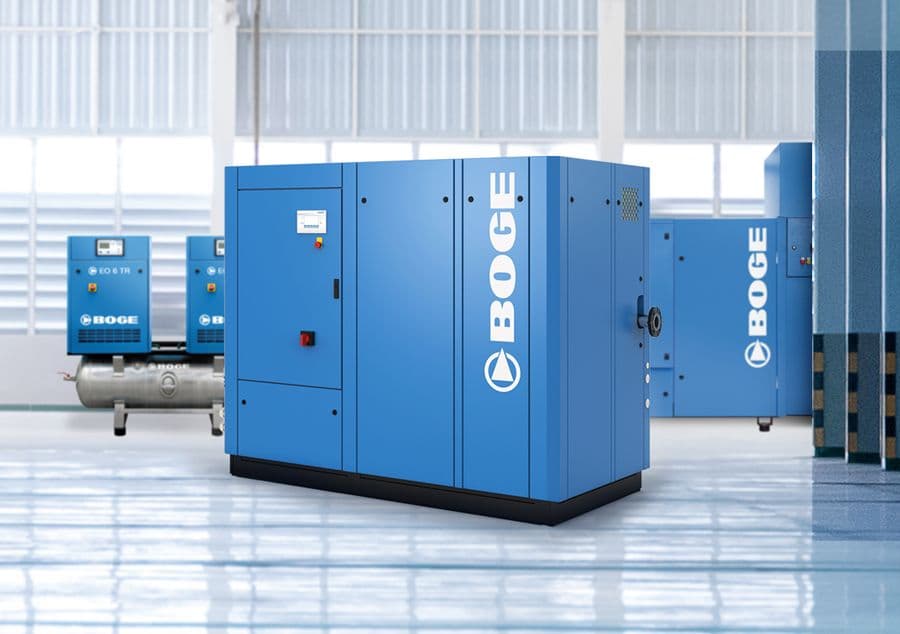 Drei gebrauchte Kompressoren von BOGE in einer hellen Lagerhalle gruppiert.